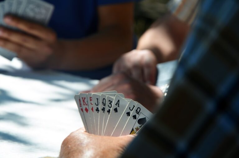 Joueurs de cartes autour d'une table, main de cartes en éventail